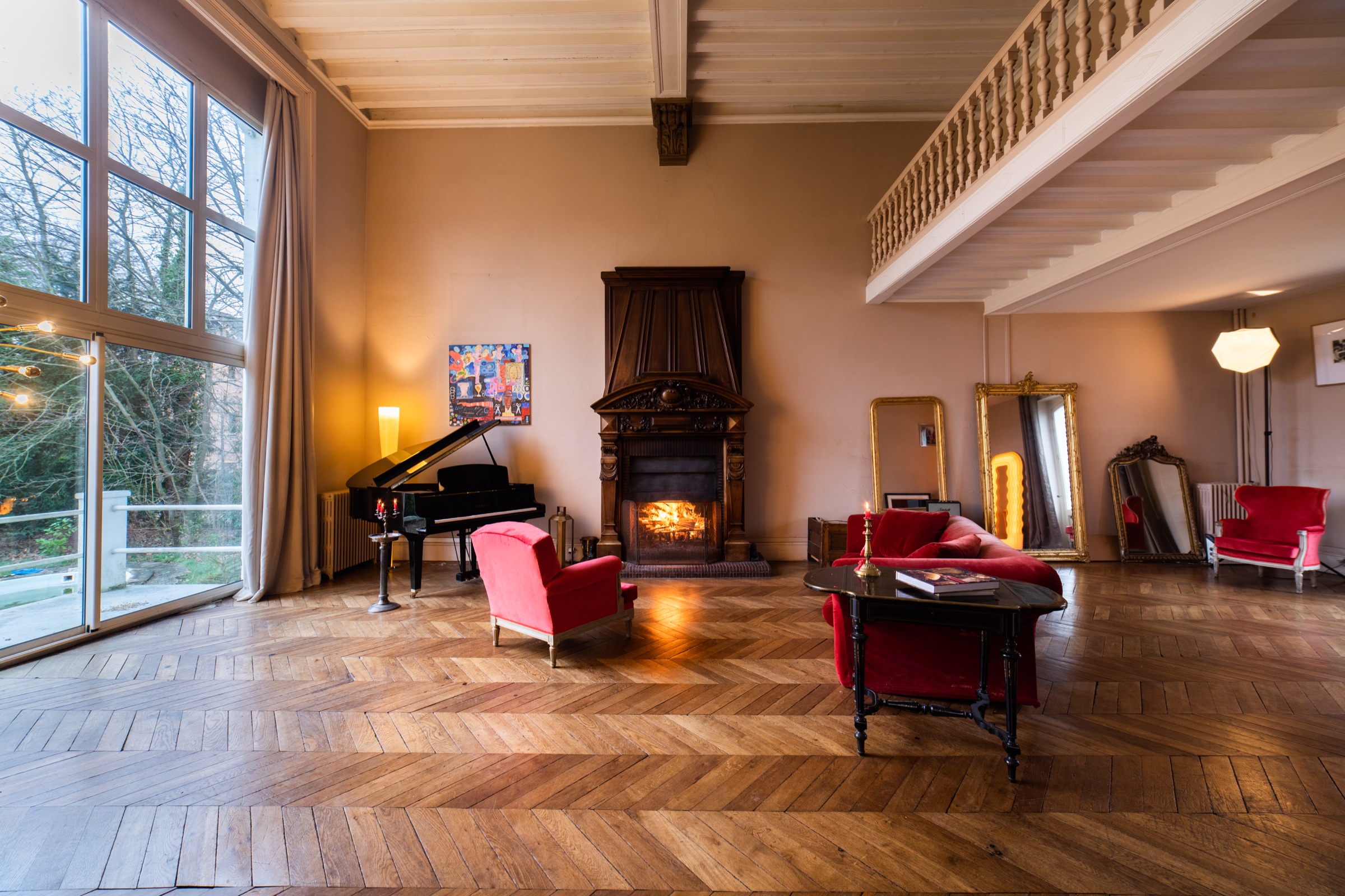 Grand salon avec cheminée, piano et fauteuils rouges